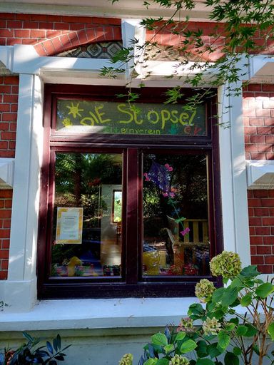 Fenster der Kinderkrippe mit handgemaltem Schriftzug Die Stöpsel
